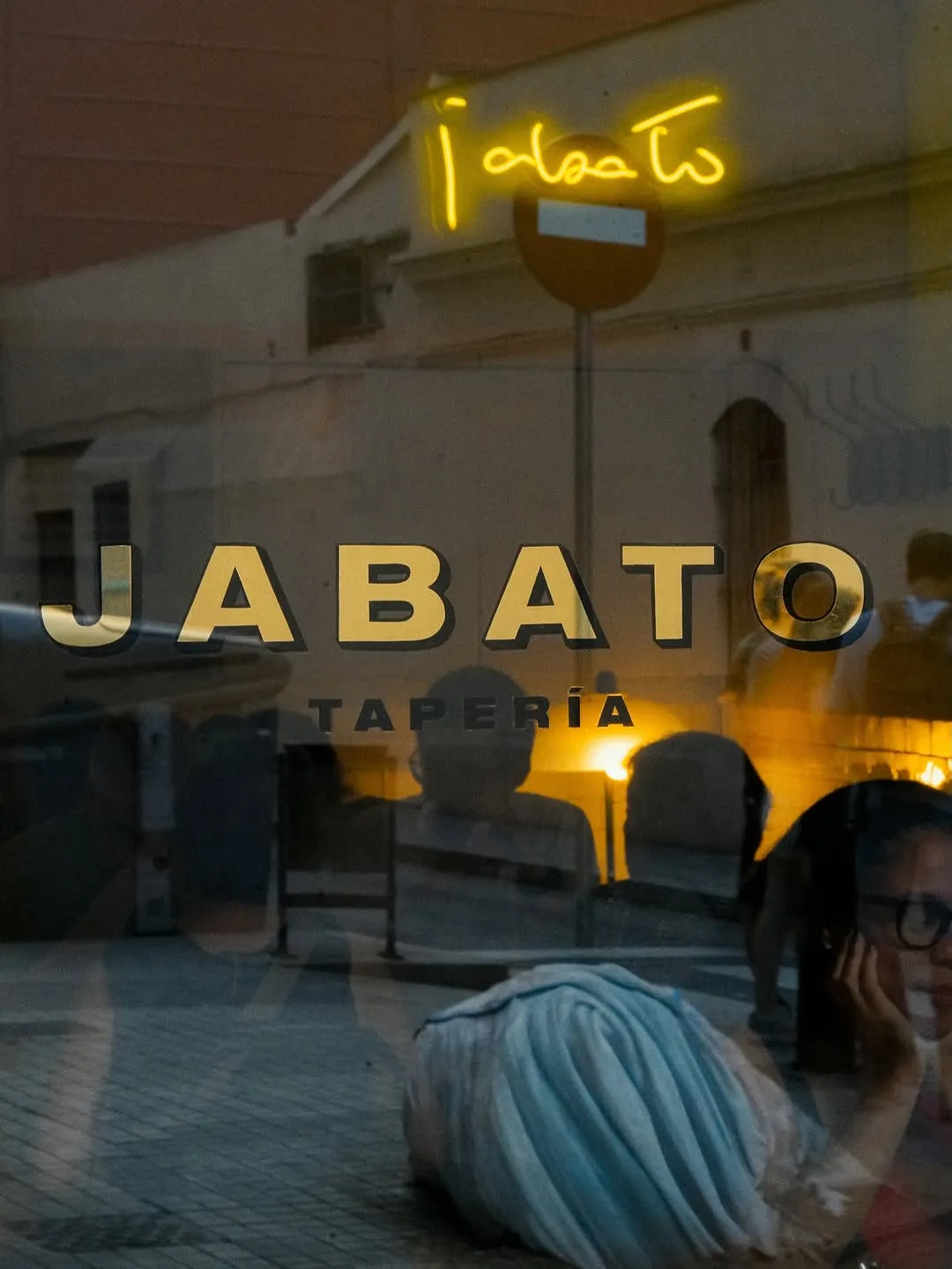 El rótulo de Jabato Tapería en el cristal, de noche