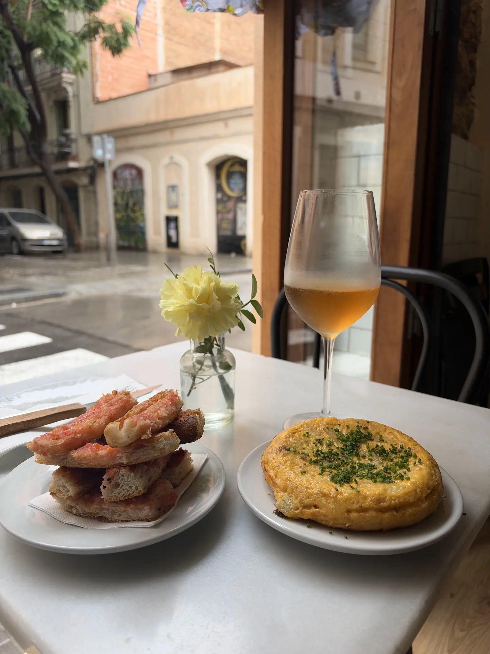 Tortilla y tostadas con una copa de vino junto a la ventana