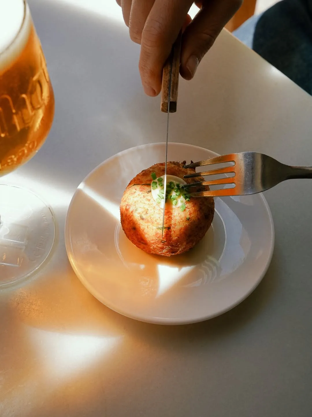 Una tapa cortada con cuchillo junto a una caña